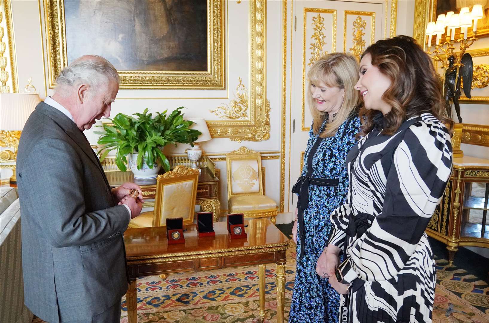 The King is presented with a £5 coin by Royal Mint CEO Anne Jessopp (centre) and director Rebecca Morgan (Jonathan Brady/PA)