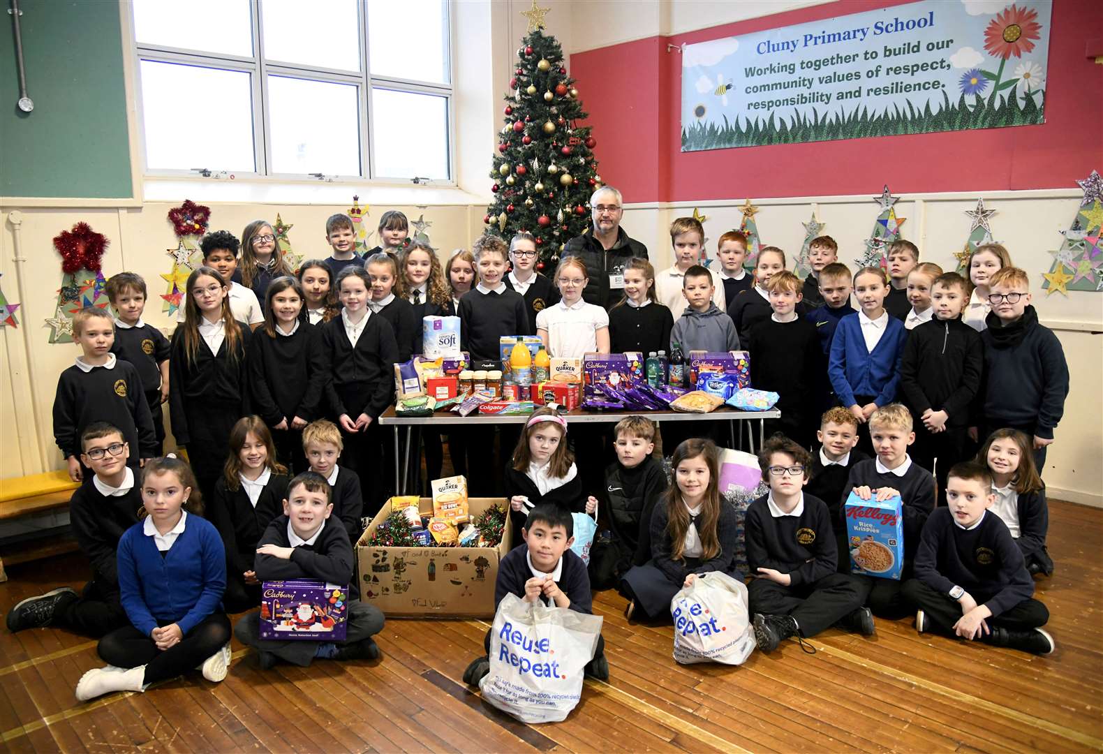 Moray Food Plus volunteer Stephen Harris (back) accepts food donations to the charity from P4/5M and P5W pupils. Picture: Beth Taylor