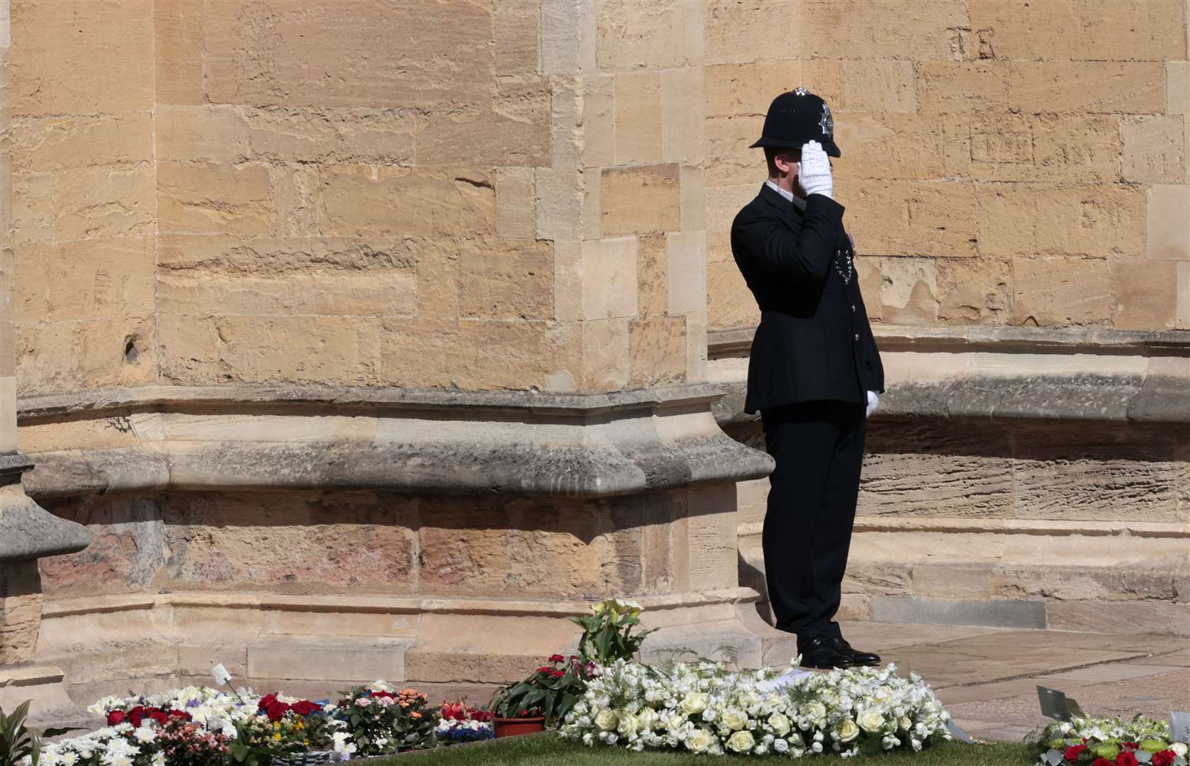 A police officer is seen giving a salute outside St George’s Chapel (Hannah McKay/PA)