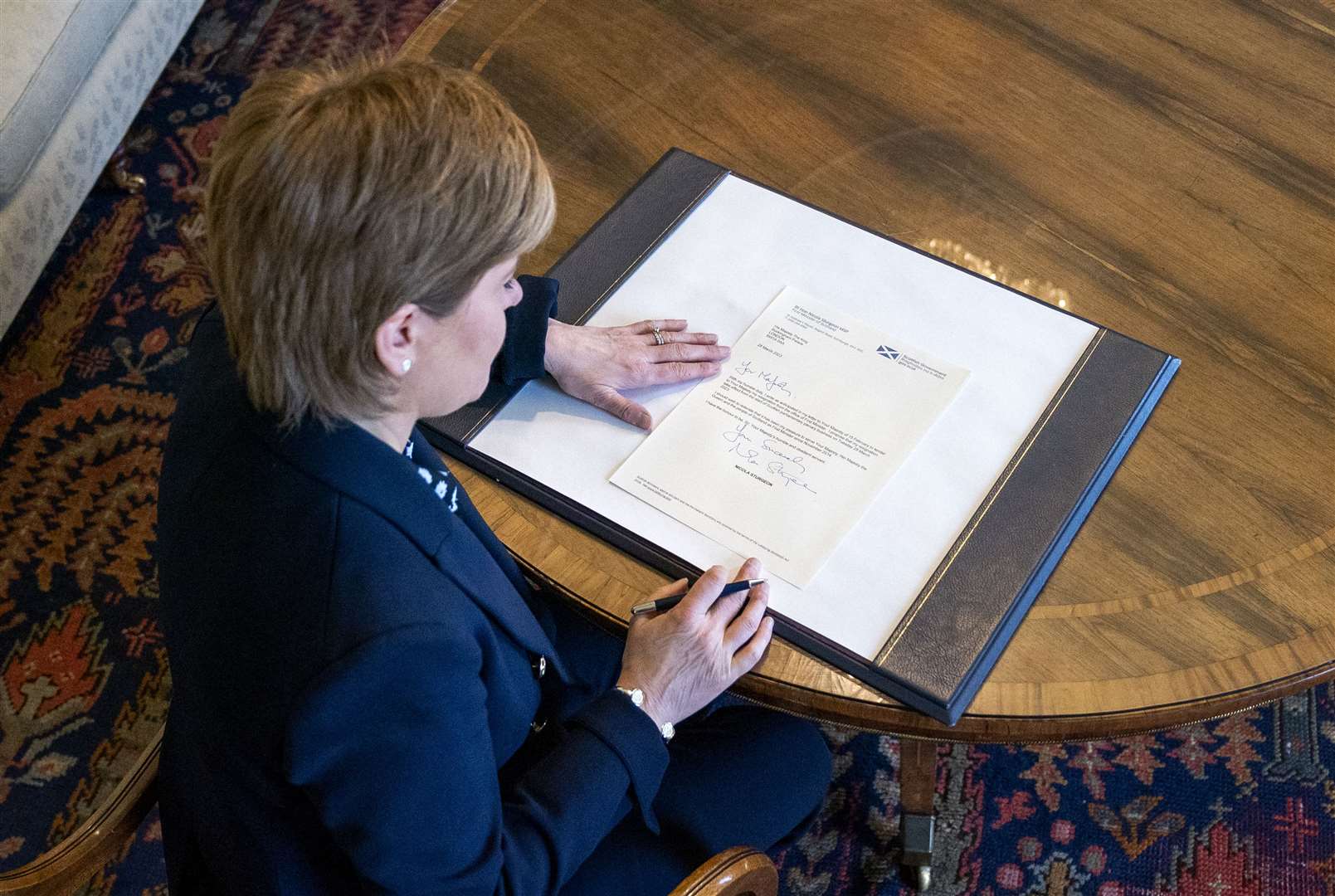 Outgoing First Minster of Scotland Nicola Sturgeon signs her official resignation letter to the King in the Drawing Room at Bute House in Edinburgh (Jane Barlow/PA)