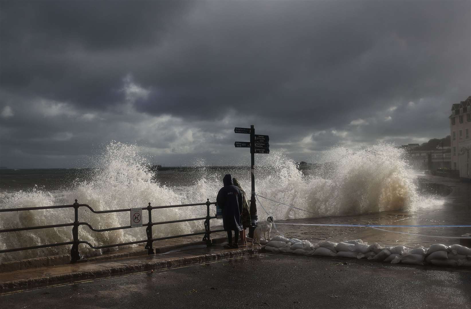 People watch the spectacle as waves crash along the coast at Swanage (Steve Parsons/PA)
