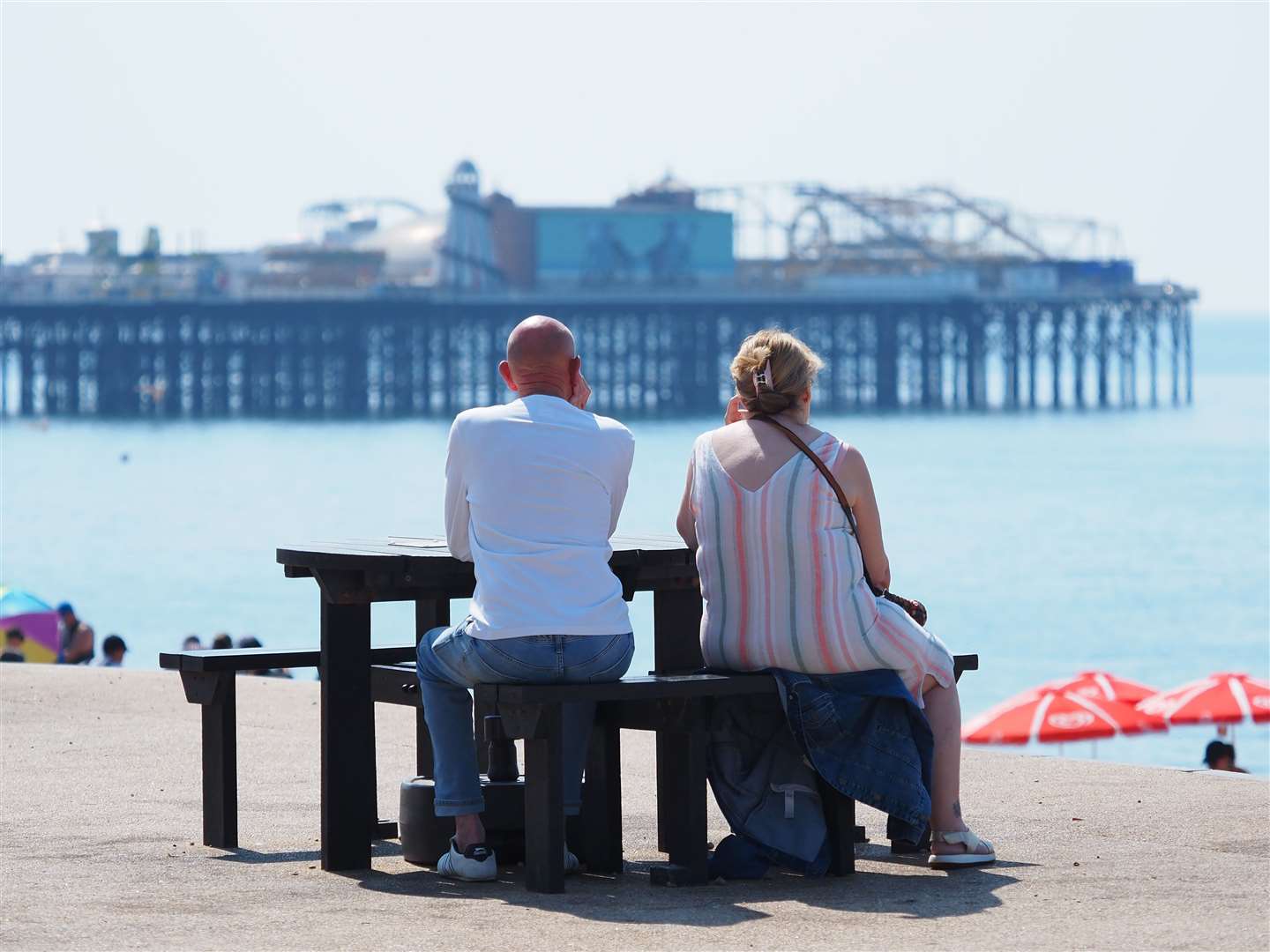 A couple sit on a bench on the seafront at Brighton beach in East Sussex (Joe Sene/PA)