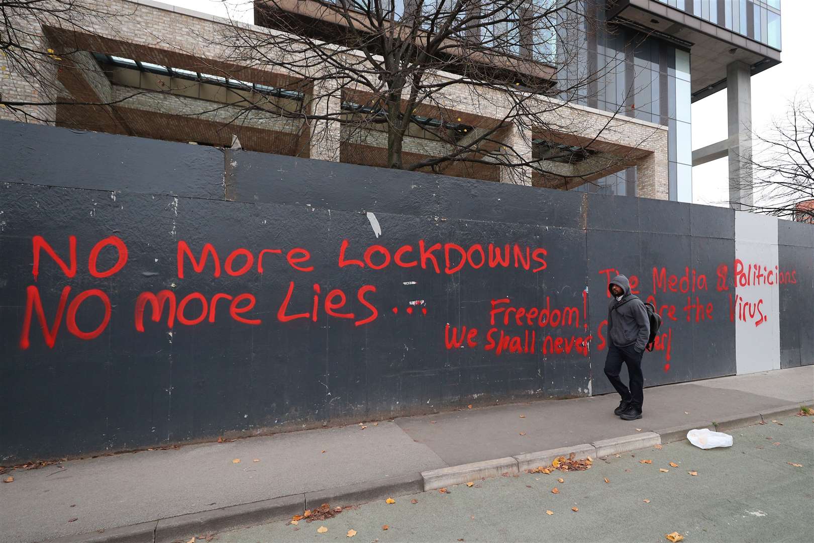 A man walks past anti-lockdown graffiti in Manchester (Peter Byrne/PA Images)