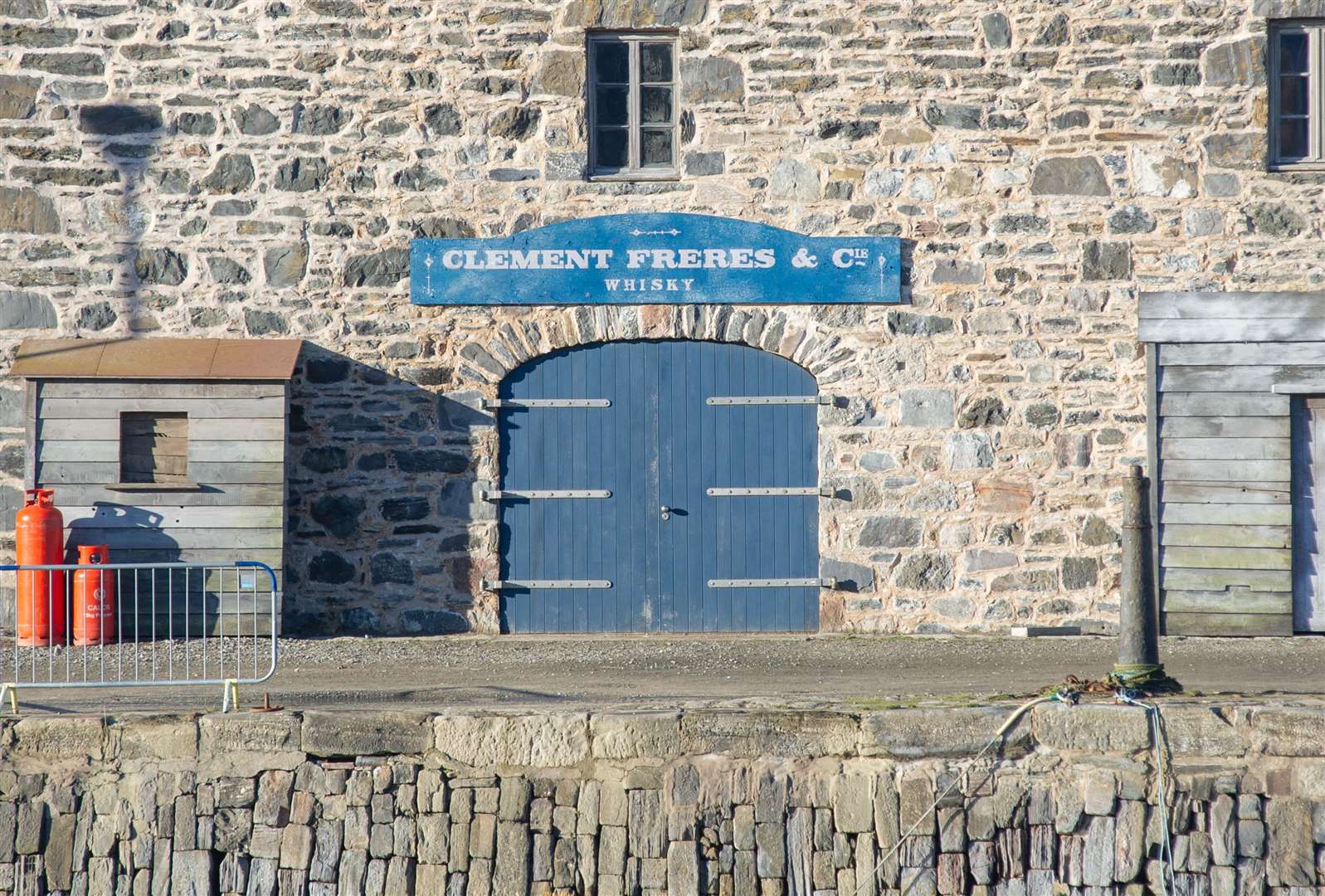 A French sign, "Clement Freres & Cie – Whisky", has been placed on a harbour-facing building and a wooden shed added to the exterior. Picture: Daniel Forsyth.