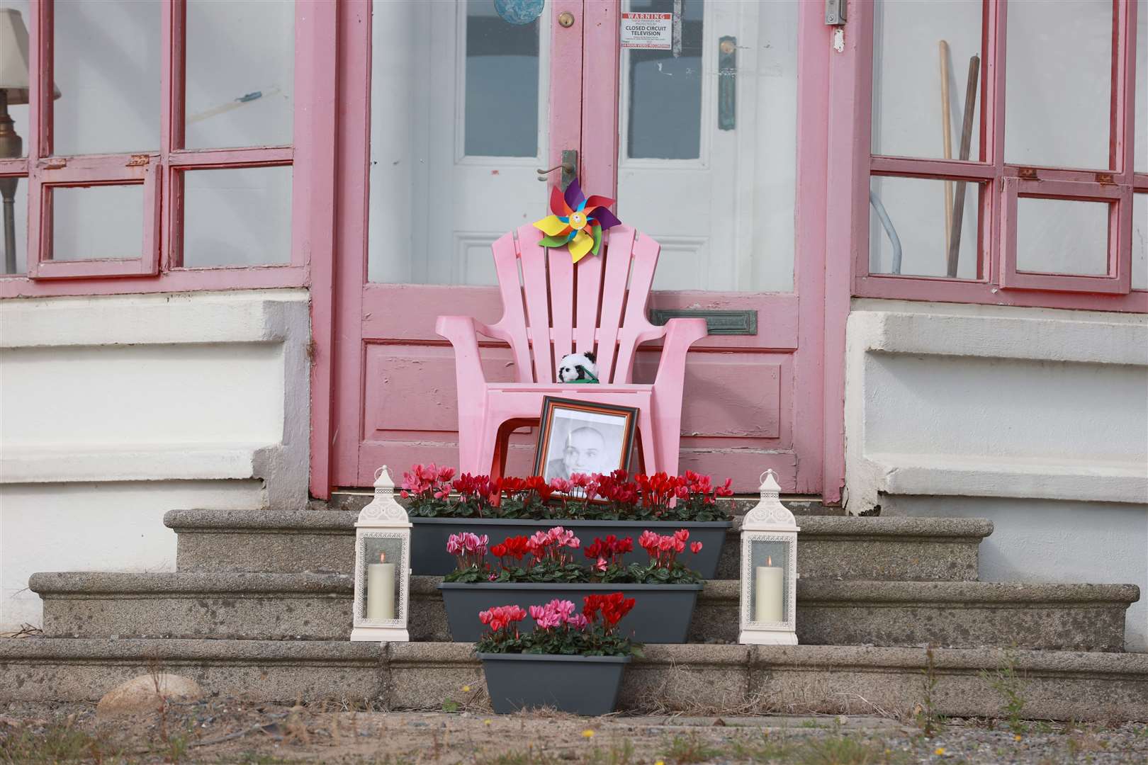 A pink chair sits outside the pink-framed conservatory of Sinead O’Connor’s former home in Bray, together with flowers, candles and a photo of the singer (Liam McBurney/PA)