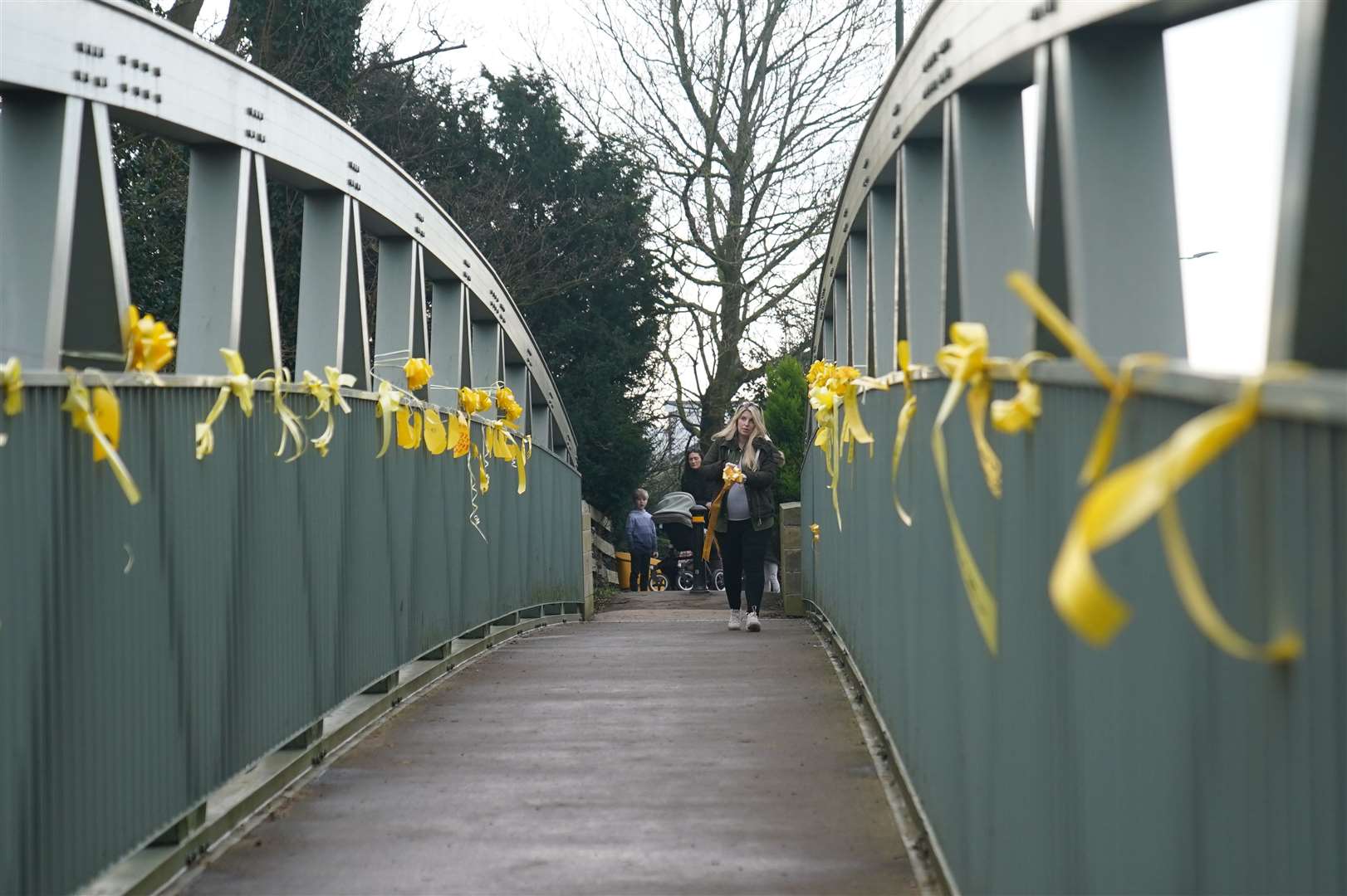 Charlotte Drake, the next-door neighbour and friend of Nicola Bulley, ties a yellow ribbon with a message of hope written on it, to a bridge over the River Wyre (Peter Byrne/PA)