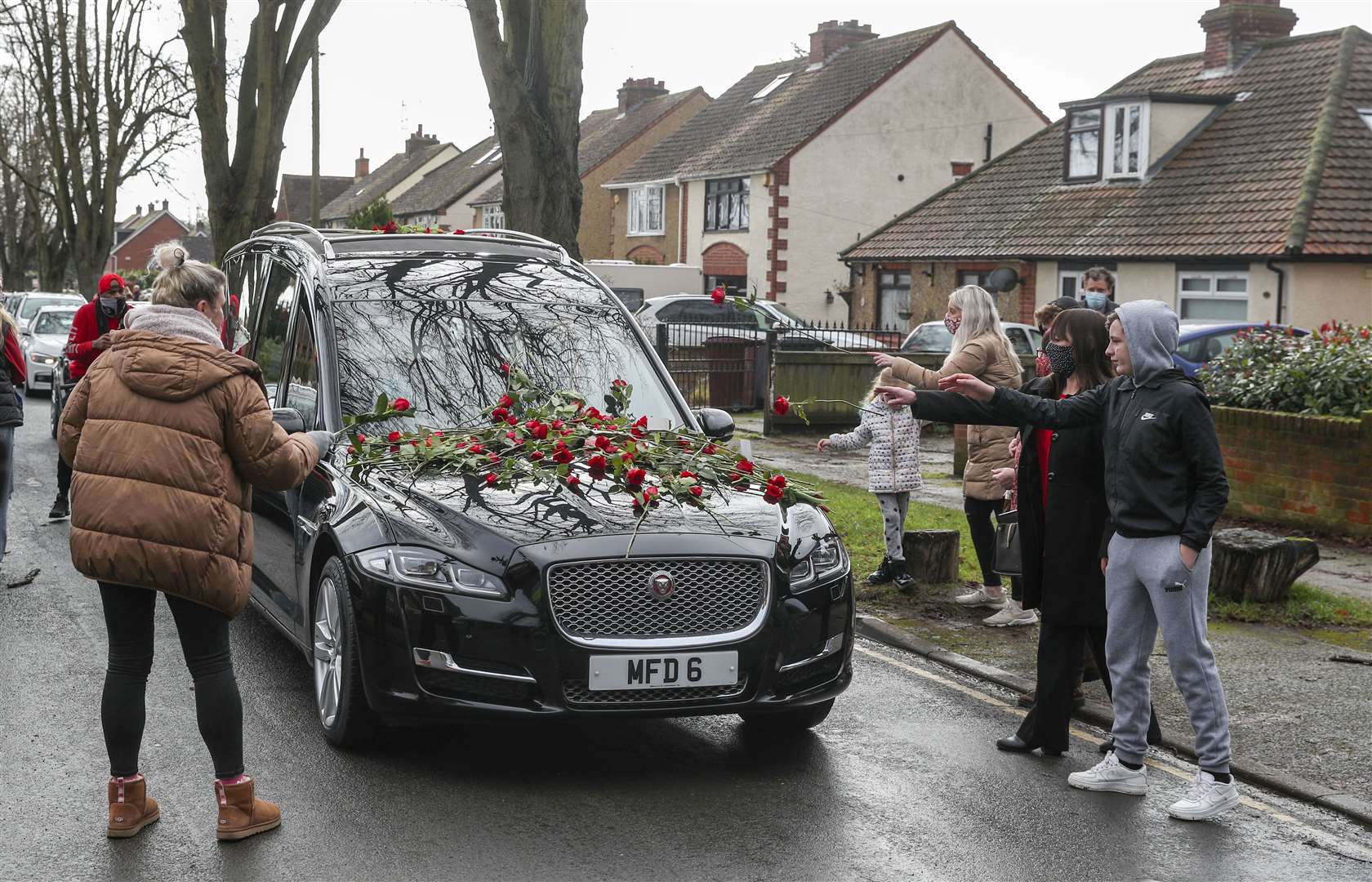 Members of the public place red roses on the hearse of Olly Stephens (PA)
