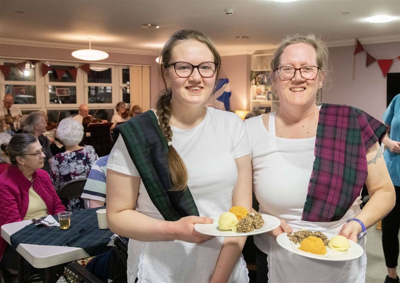 Jessica Davey (left) and Katie Hopewell (right) handing out the Haggis, neeps and tatties. ..Balhousie Care Home Burns Supper in Huntly...Picture: Beth Taylor.