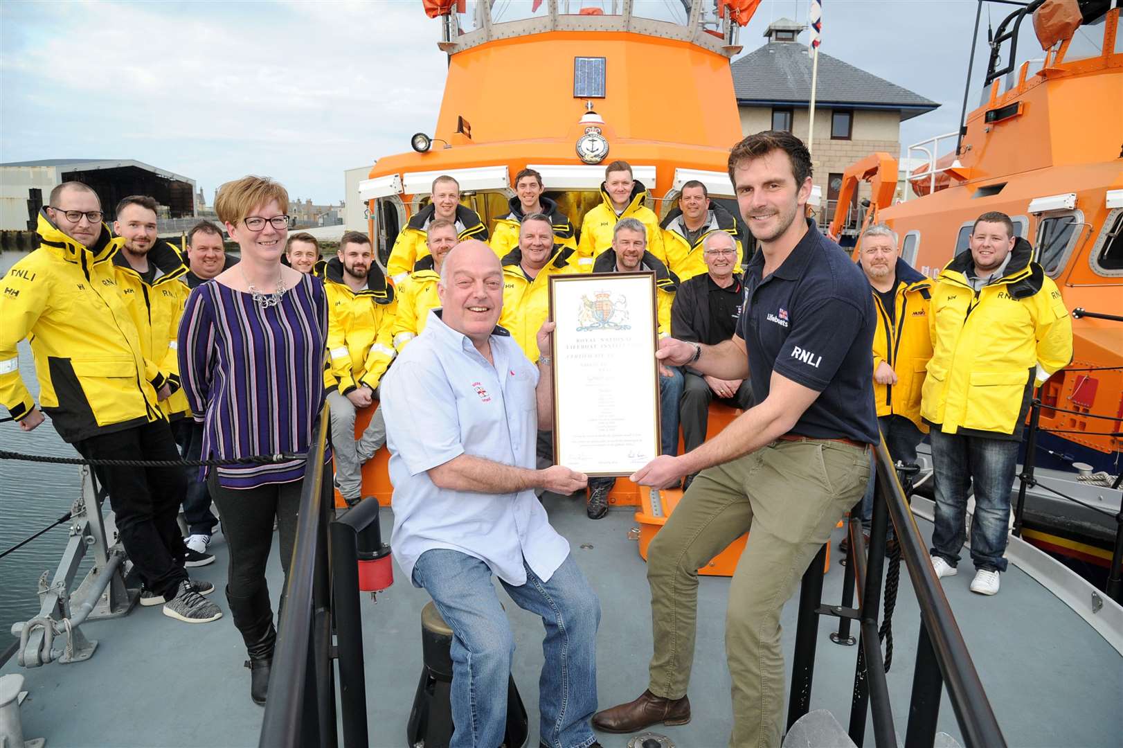 Gordie Lawtie (front left) is presented with this retirement vellum by RNLI ALM Henry Weaver. Mr Lawtie is joined by wife Lesley and the Buckei lifeboat crew. Picture: Eric Cormack. Image No.(043638)