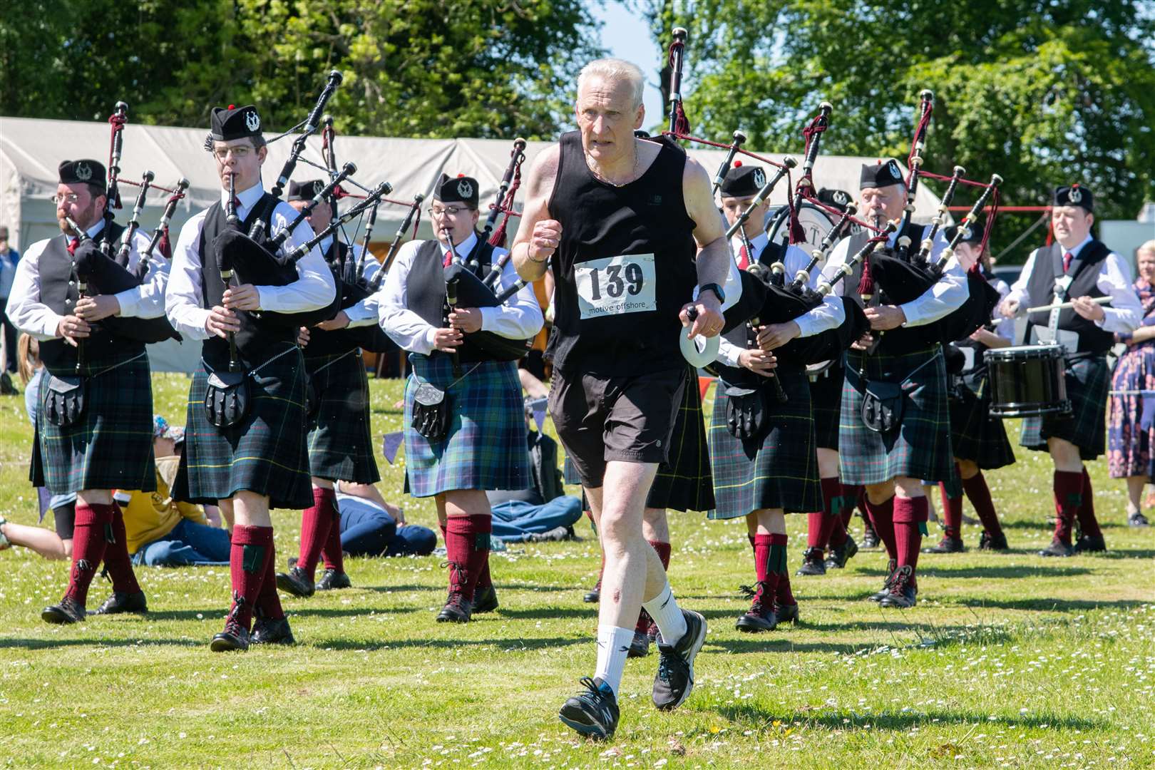 Knock Hill Race Runner #139 Charlie Simpson runs past the Portsoy Pipe Band as he approaches the finish of the race...Cornhill Highland Games - Saturday 4th June 2022...Picture: Daniel Forsyth..