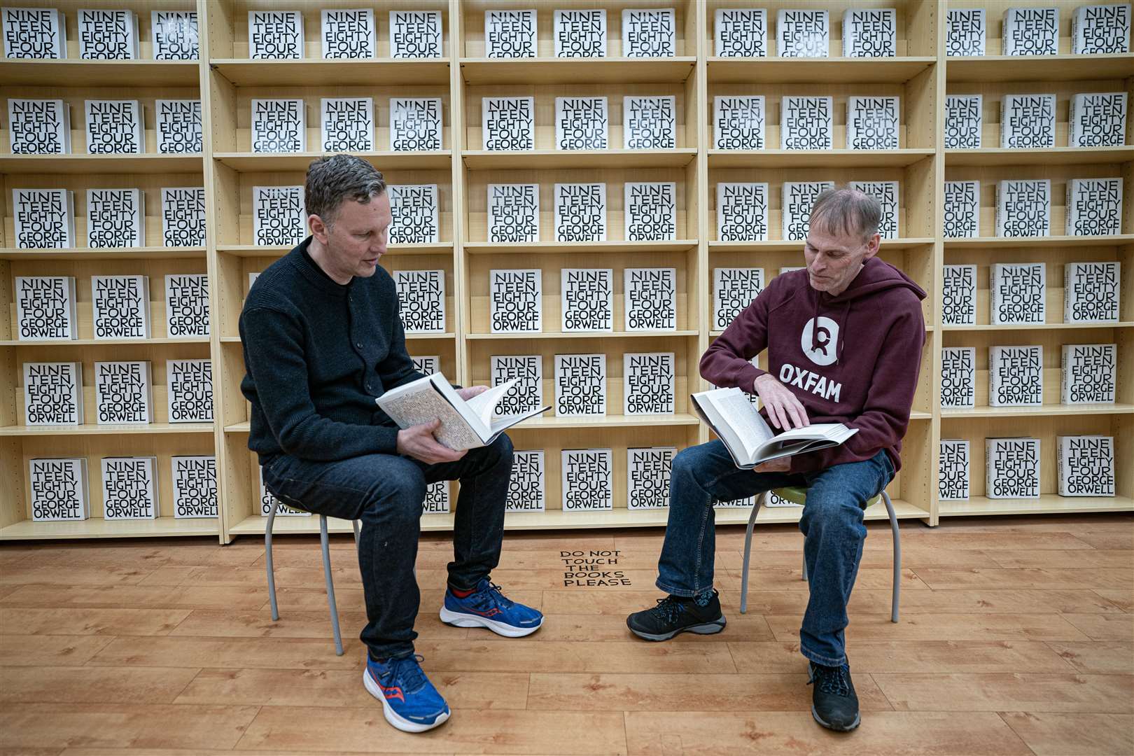 David Shrigley and Phil Broadhurst, from Oxfam, leaf through books as they chat about David’s Pulped Fiction installation in Swansea (Ben Birchall/PA)