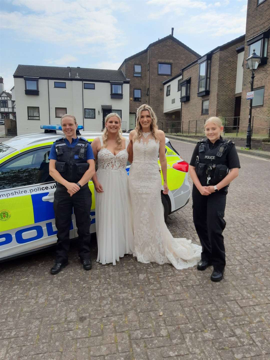 Sian (left) and Jemma Batchelor-Thomas with police officers after catching a lift in a police car to their wedding (Hampshire and Isle of Wight Constabulary/PA)